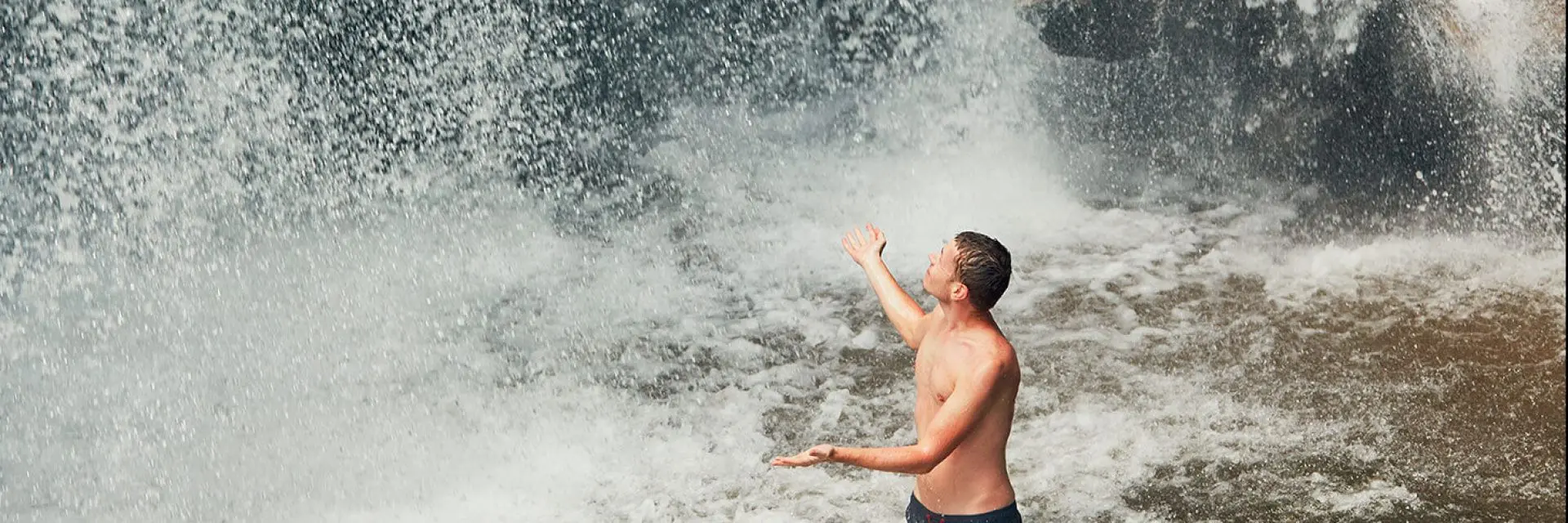 Imagem de um homem nadando em uma cachoeira